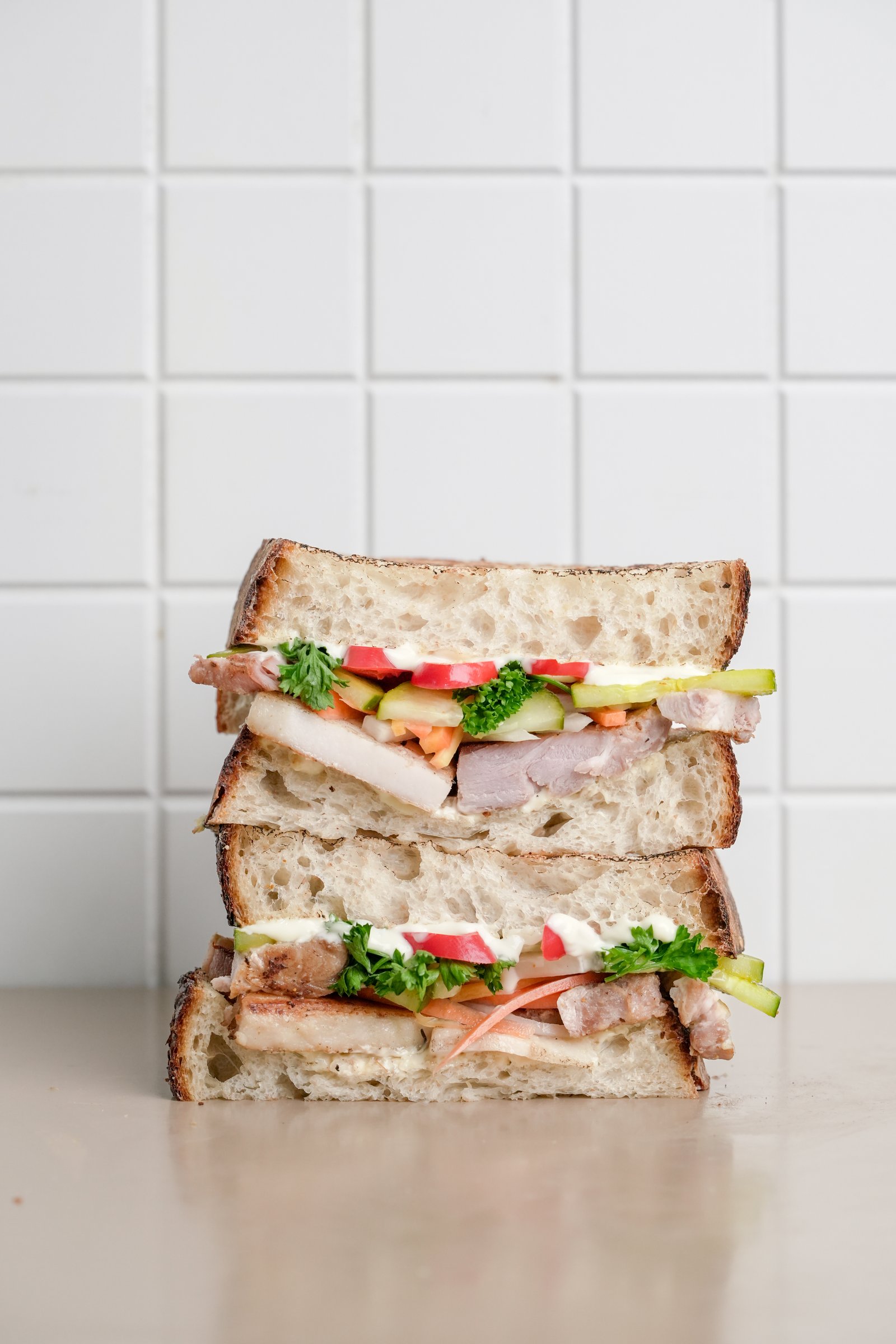 Crispy Pork Belly — sourdough, pork belly, pickled medley, sweet chilli, mayo, cucumber, cilantro, red chilli