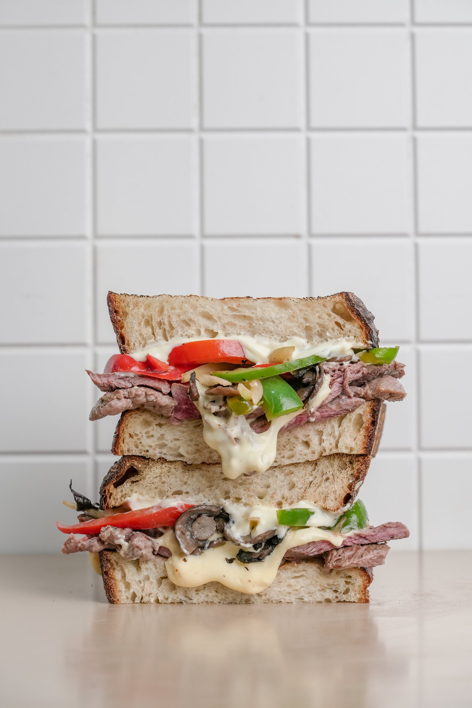 The Steak — sourdough, beef tenderloin, mushroom, onion, green bell pepper, cheese sauce, butter